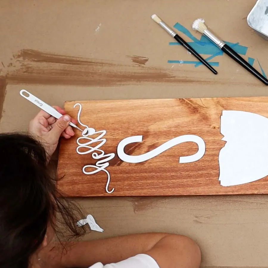 using tweezers to remove stencil vinyl from wood