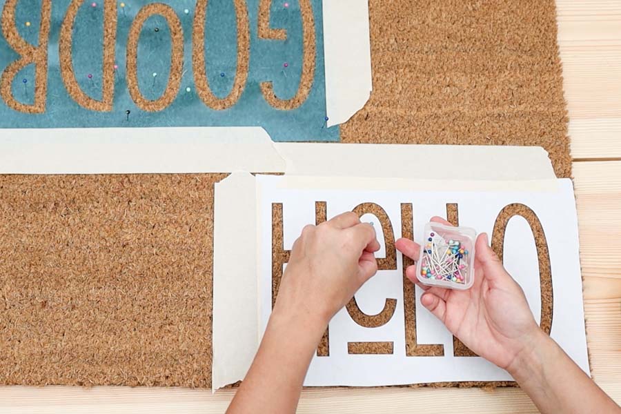 securing freezer paper stencil with sewing pins and masking tape