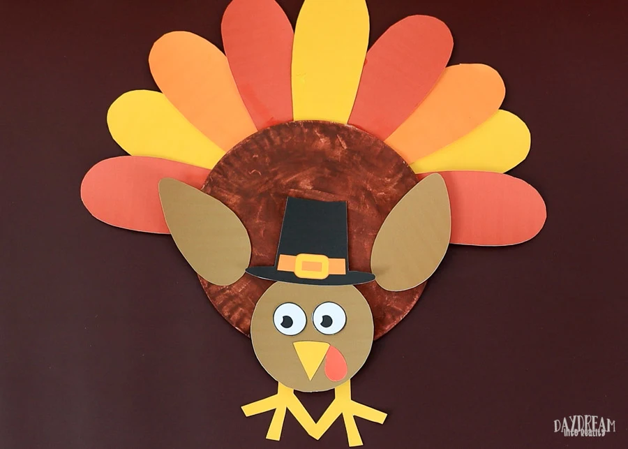 cute turkey craft for kids with pilgrim hat and looking down.