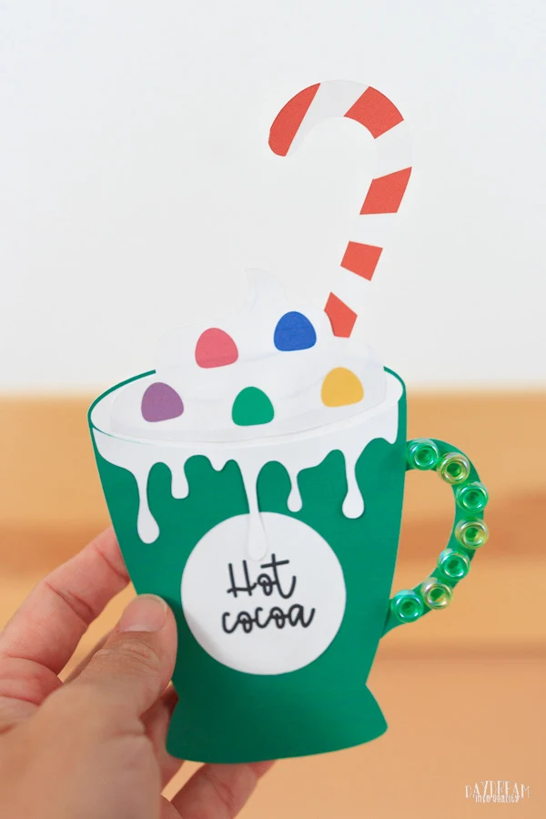 paper hot cocoa craft for kids - green mug with beads, candy cane and whipped cream.