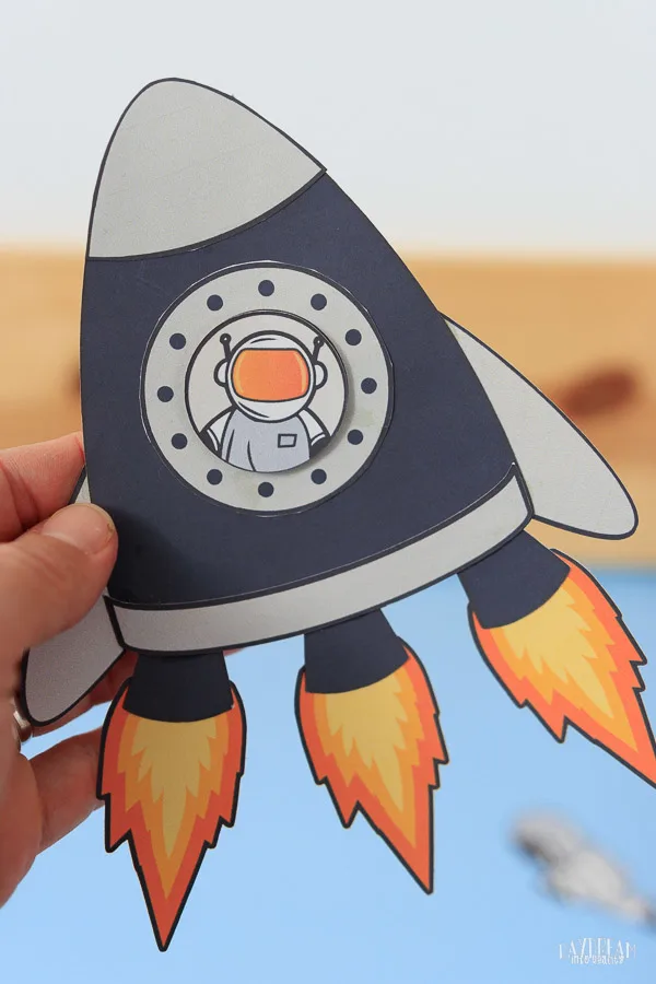 paper rocket craft with three fire exhaust flames and astronaut inside it.