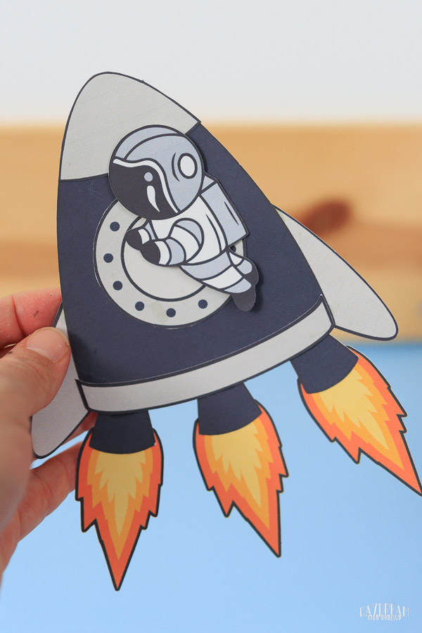 paper rocket craft with three fire exhaust flames and astronaut hovering.